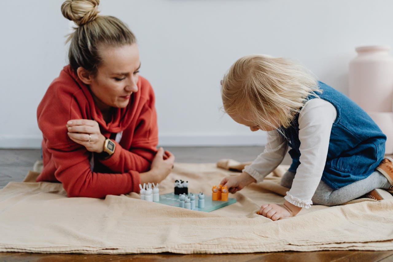 Tender moment of mother and daughter enjoying a chess game indoors, fostering family bonding.